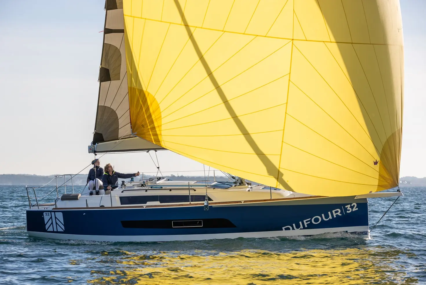 Dufour 32 — Voilier bleu et blanc naviguant sous voile avec deux personnes à bord.