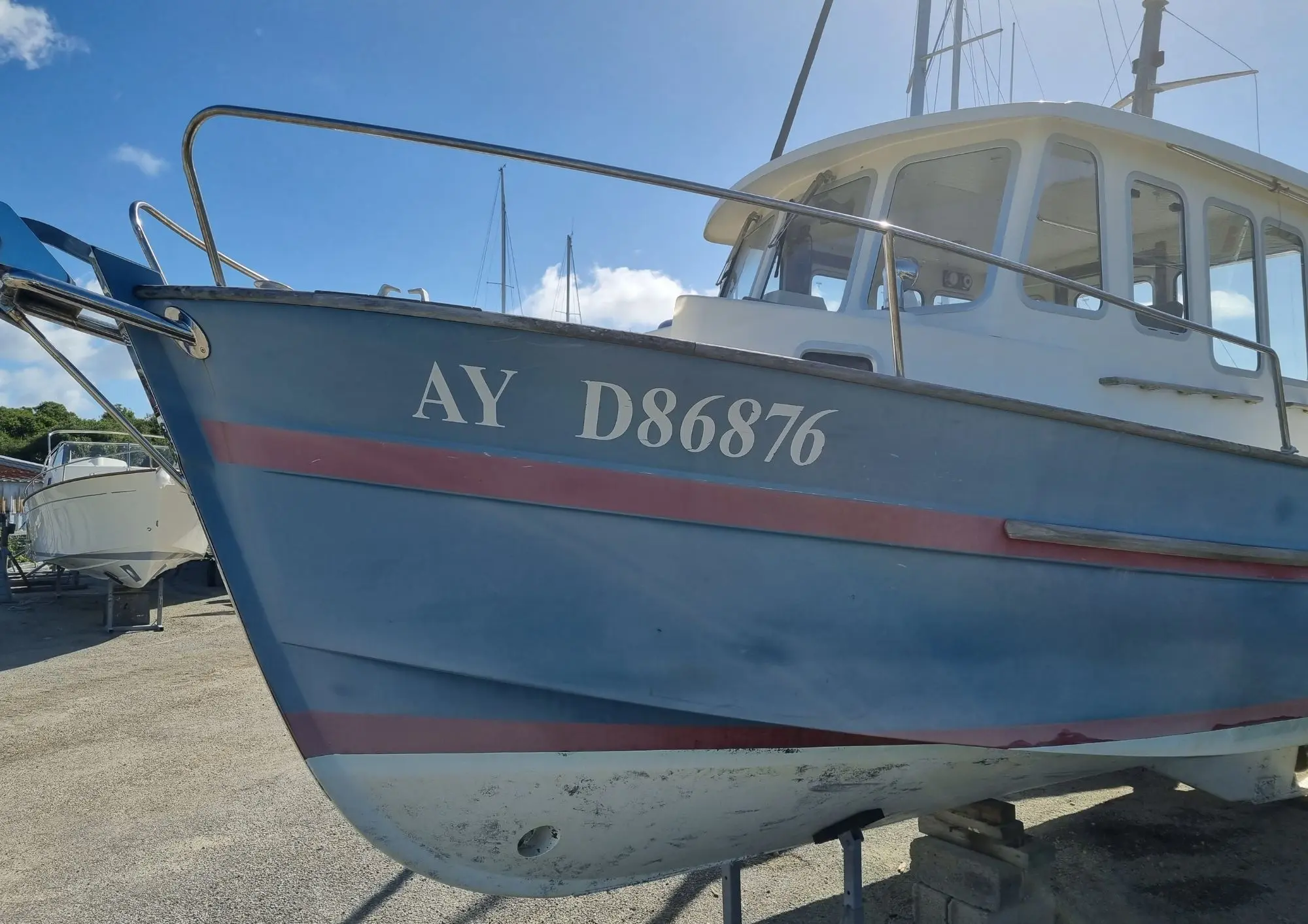 Rhea 28 — Vue rapprochée de l’étrave et de la timonerie d’un bateau bleu à terre.