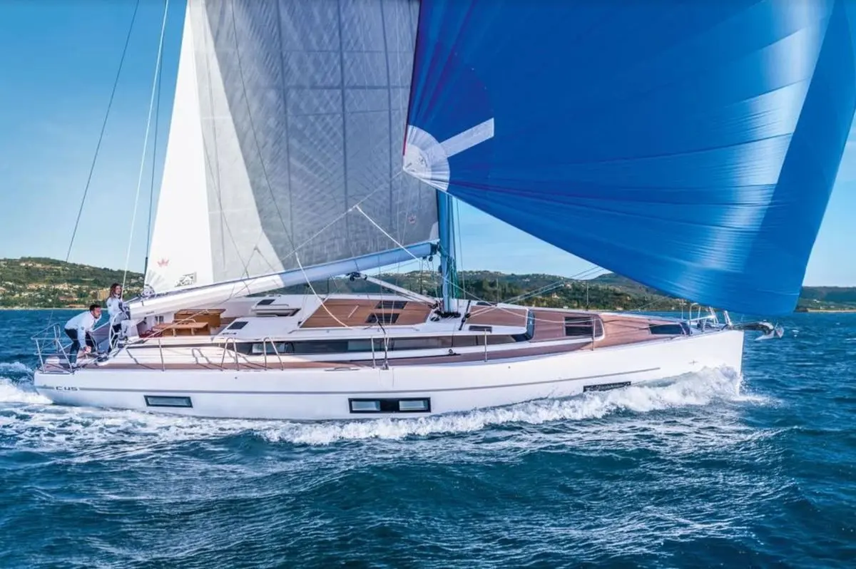 Bavaria C45 — Voilier blanc sous voiles naviguant près d’une côte, vu de profil.