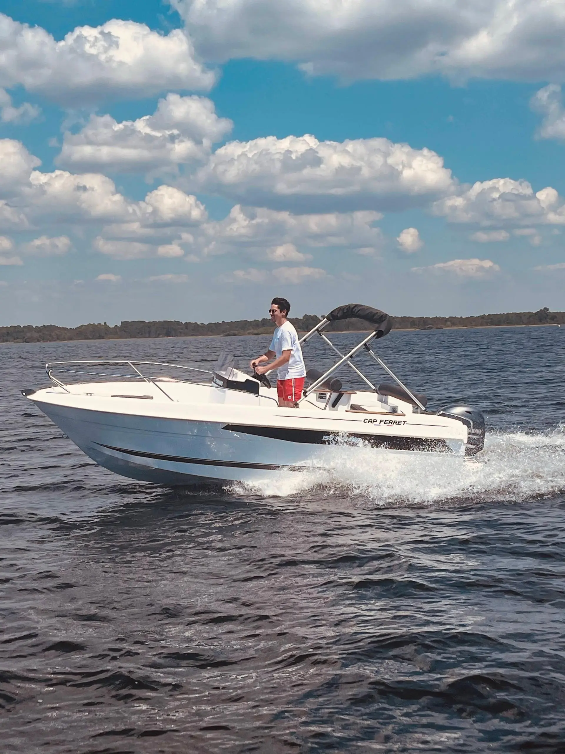 B2 Marine 155 — Bateau à moteur blanc naviguant sur l’eau, avec un passager à la barre.