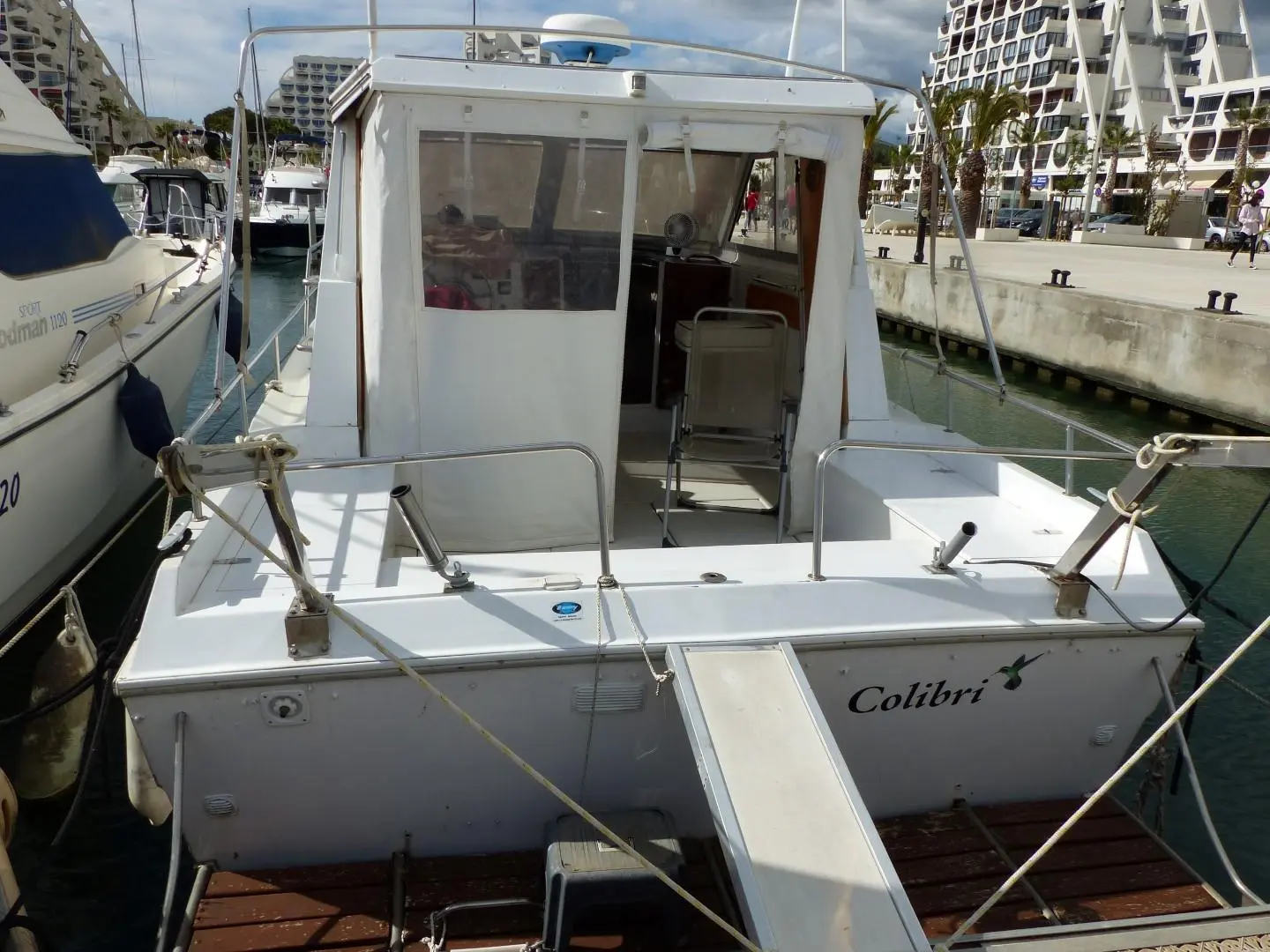 Arcoa 970 — Vue arrière d’un bateau blanc amarré dans une marina.