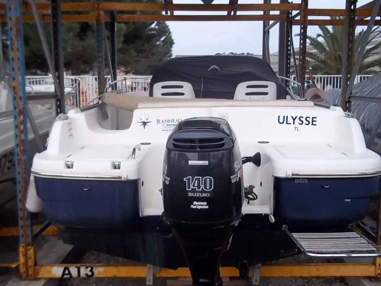 Jeanneau Cap Camarat 625 — Vue arrière d’un bateau blanc et bleu équipé d’un moteur hors-bord.