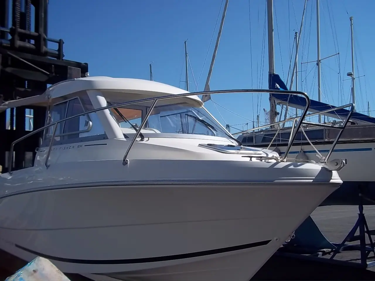 Jeanneau Merry Fisher 595 — Vue latérale avant d’un bateau à cabine, amarré dans une marina.