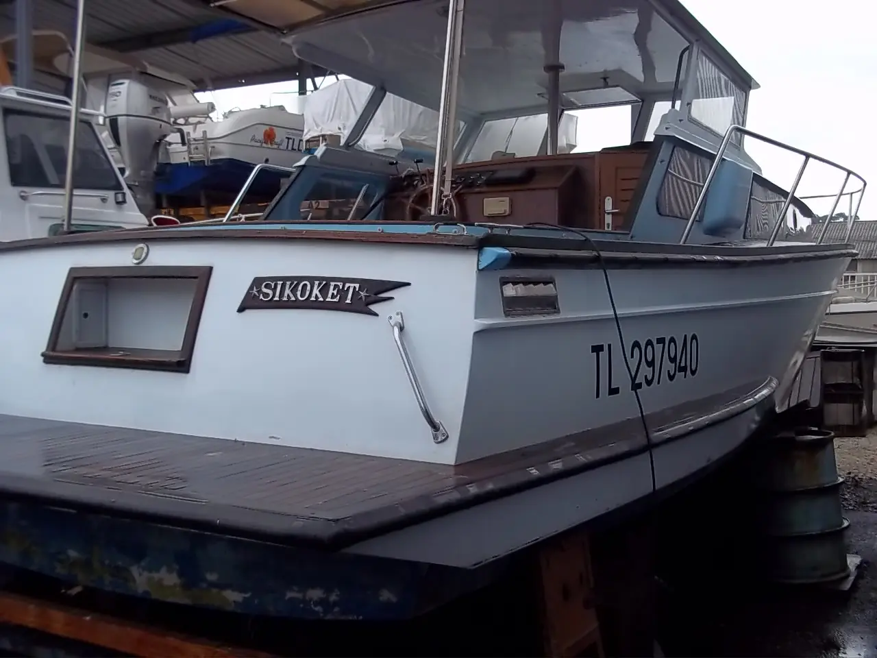 Polyboat Polyflash — Bateau à cabine vu de trois quarts arrière sous un abri, avec immatriculation visible.