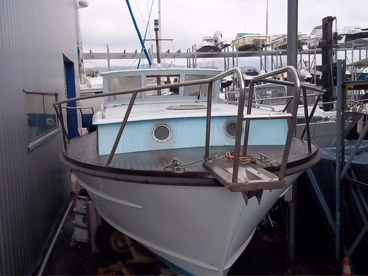 Polyboat Polyflash — Bateau blanc et bleu vu de l’avant, stationné sur un support dans un chantier naval.