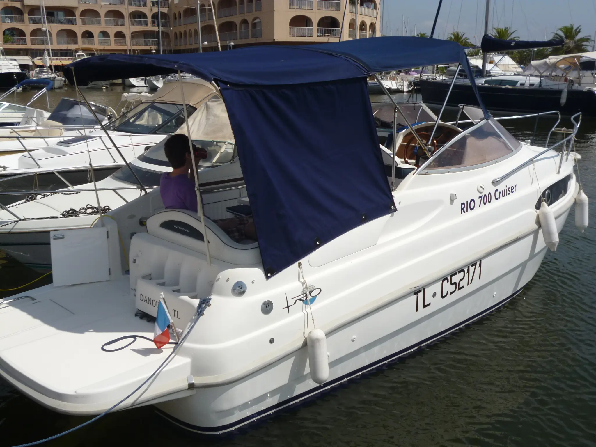 Rio 700 — Bateau à moteur blanc photographié de trois quarts arrière dans un port.
