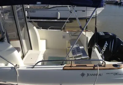 Jeanneau Merry Fisher 725 — Vue partielle de l’arrière d’un bateau Jeanneau, avec cockpit et moteur hors-bord.