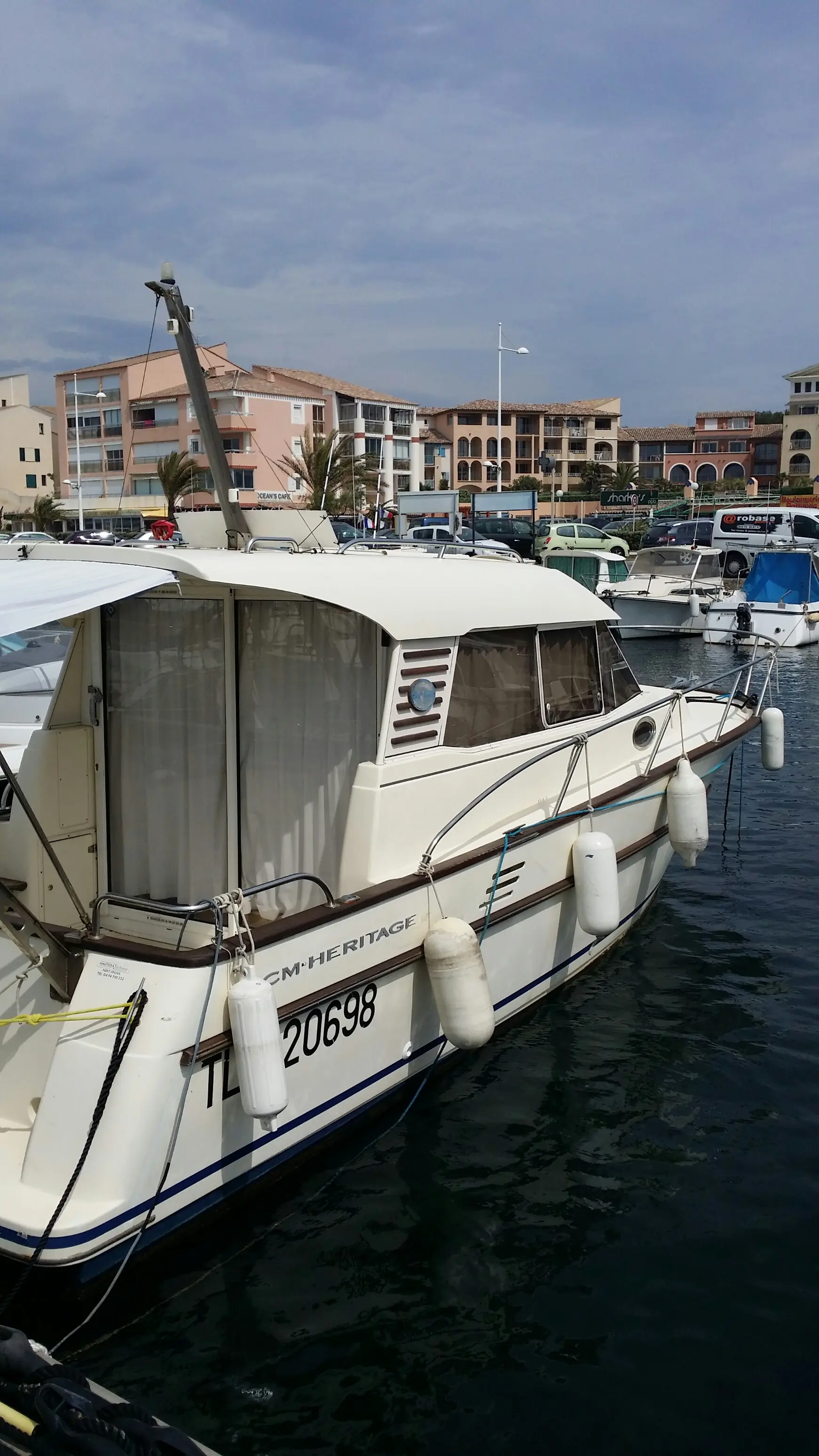 ACM Heritage — Bateau à moteur blanc amarré dans un port, vu de trois quarts côté tribord.
