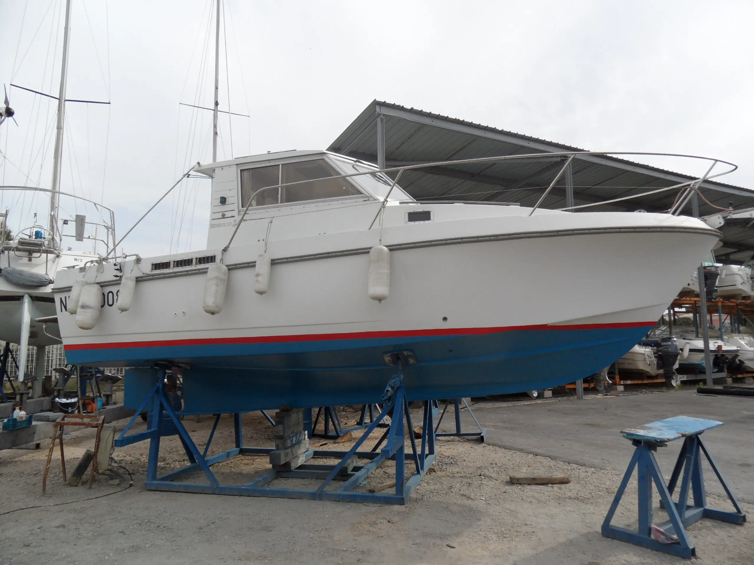 Beneteau Antares 800 — Bateau à moteur blanc et bleu posé sur bers dans un chantier naval.