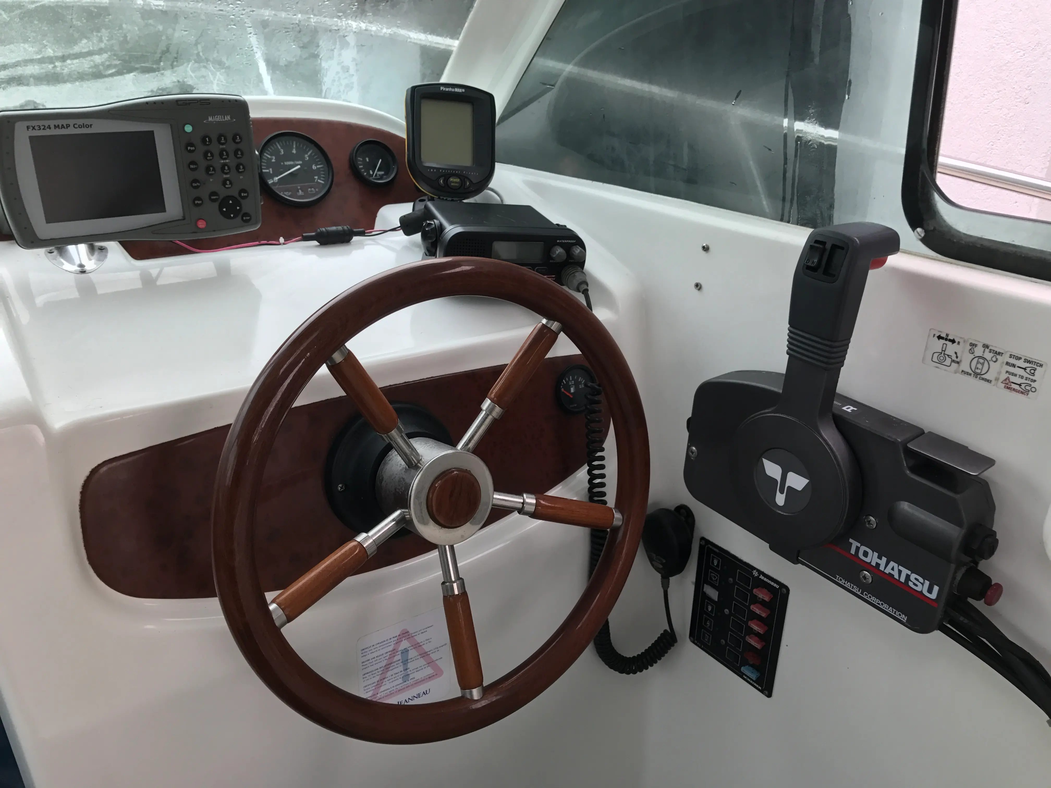 Jeanneau Merry Fisher 625 — Poste de pilotage avec roue, instruments de navigation et commande moteur hors-bord.