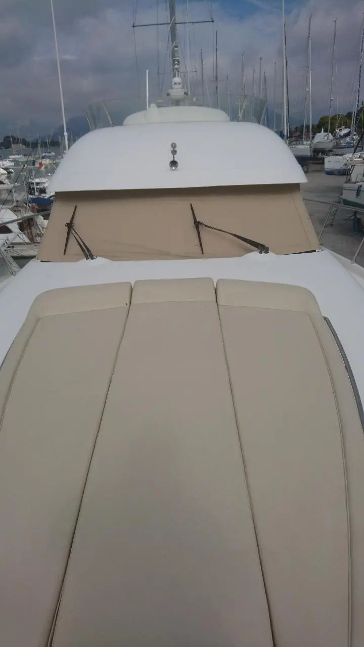 Jeanneau Prestige 46 — Vue du bain de soleil avant et du pare-brise d’un bateau amarré au port.