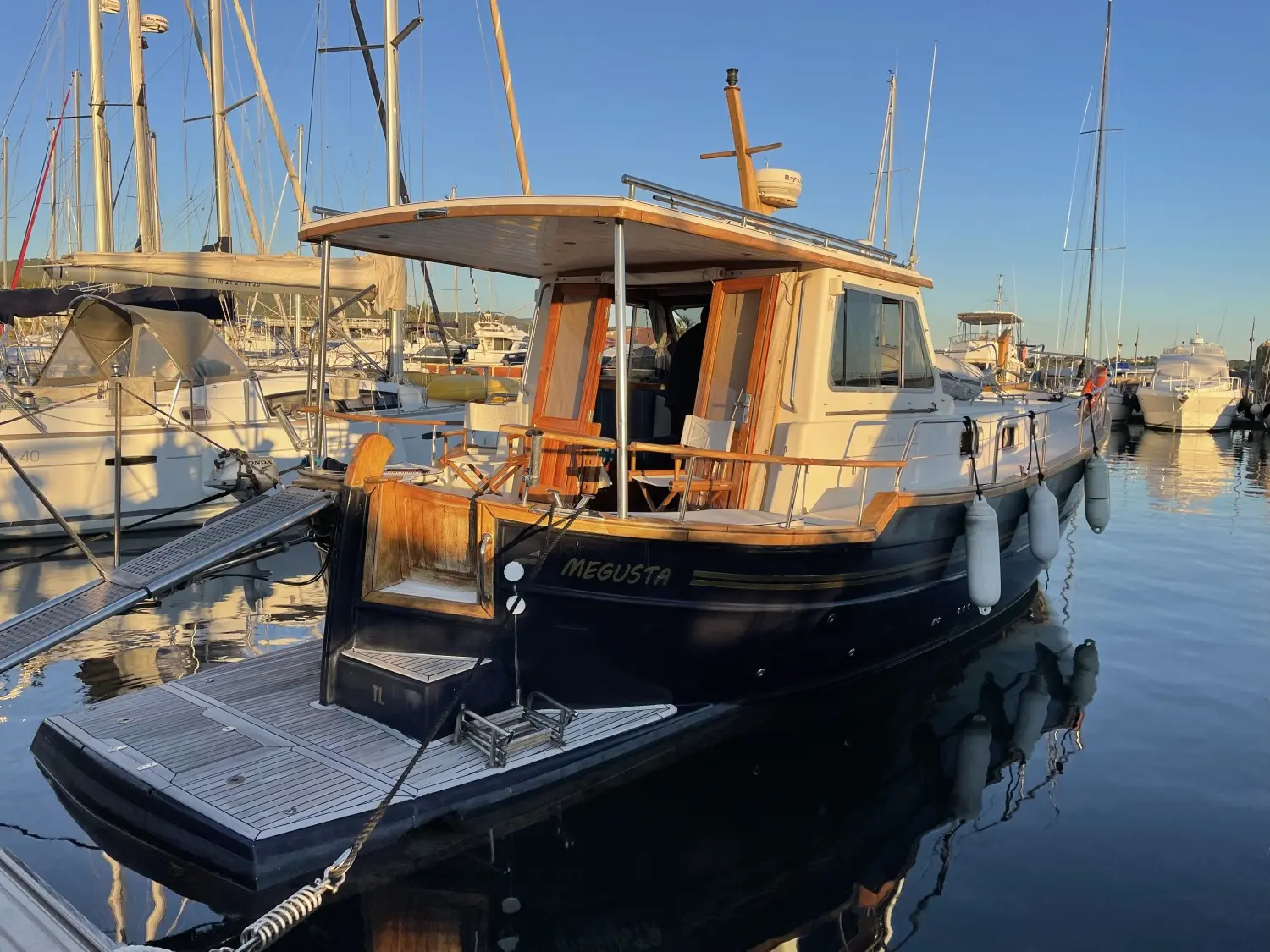 Menorquin 120 — Bateau à moteur vu de trois quarts arrière dans un port de plaisance.