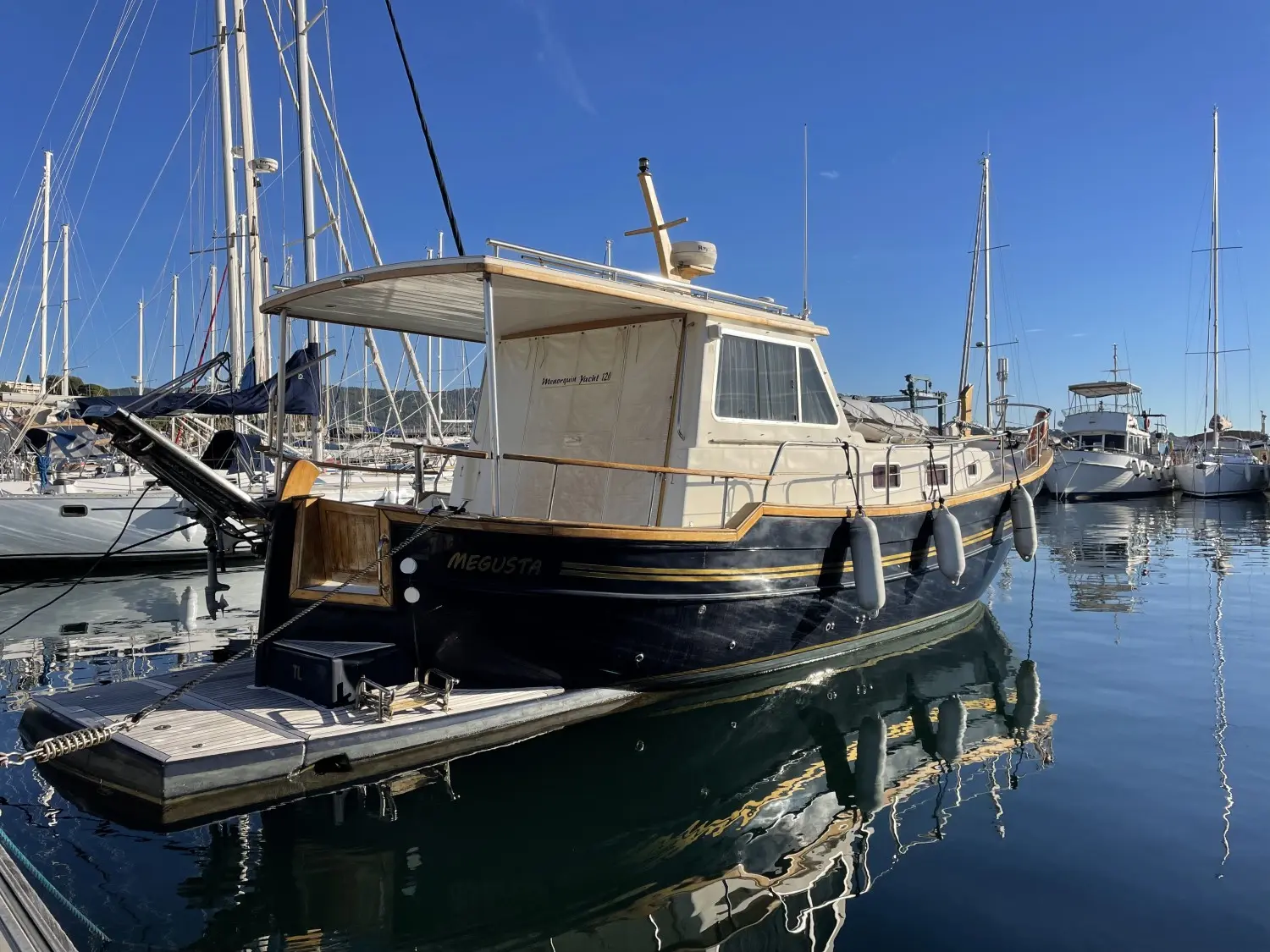 Menorquin 120 — Bateau à moteur vu de trois quarts arrière dans un port de plaisance.