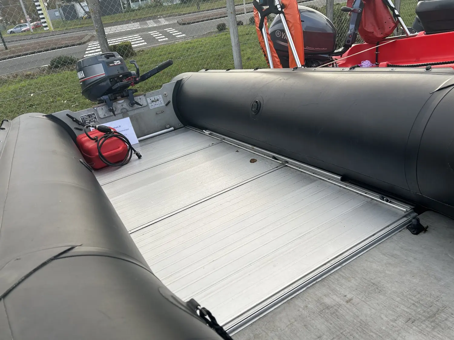 Bombard Commando C4 Noir — Vue de l’arrière d’un bateau pneumatique avec moteur hors-bord et plancher métallique.