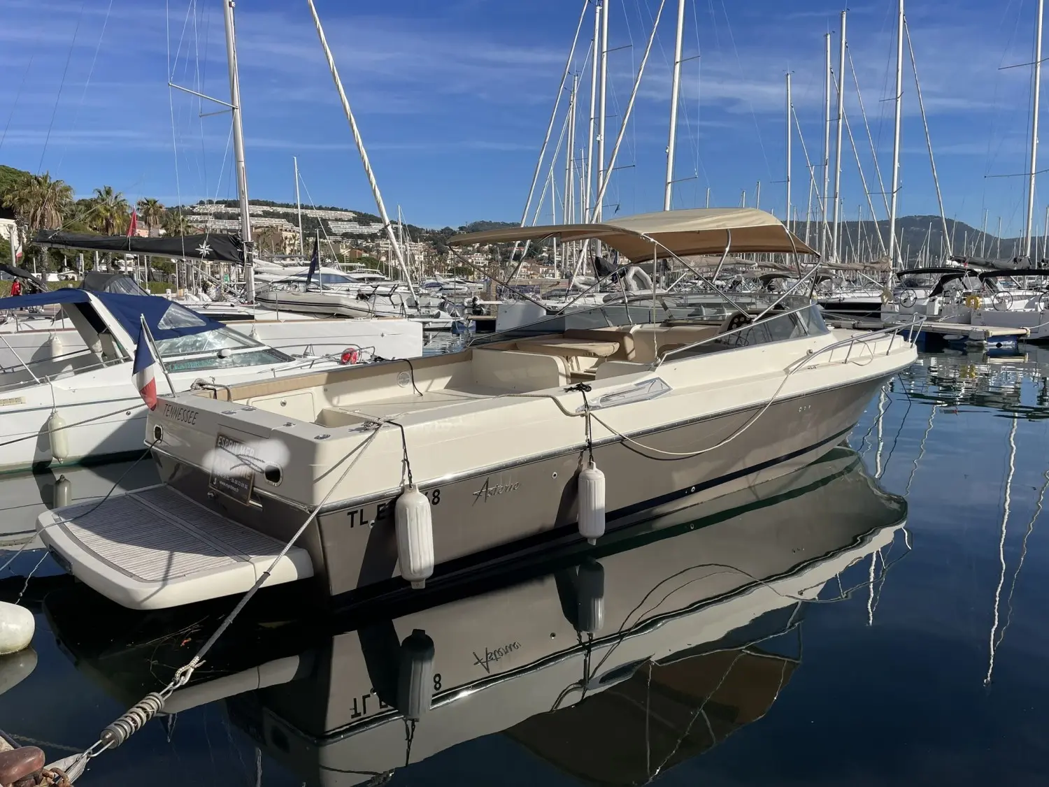 Asterie 40 — Bateau à moteur beige amarré dans une marina, vu de trois quarts arrière.