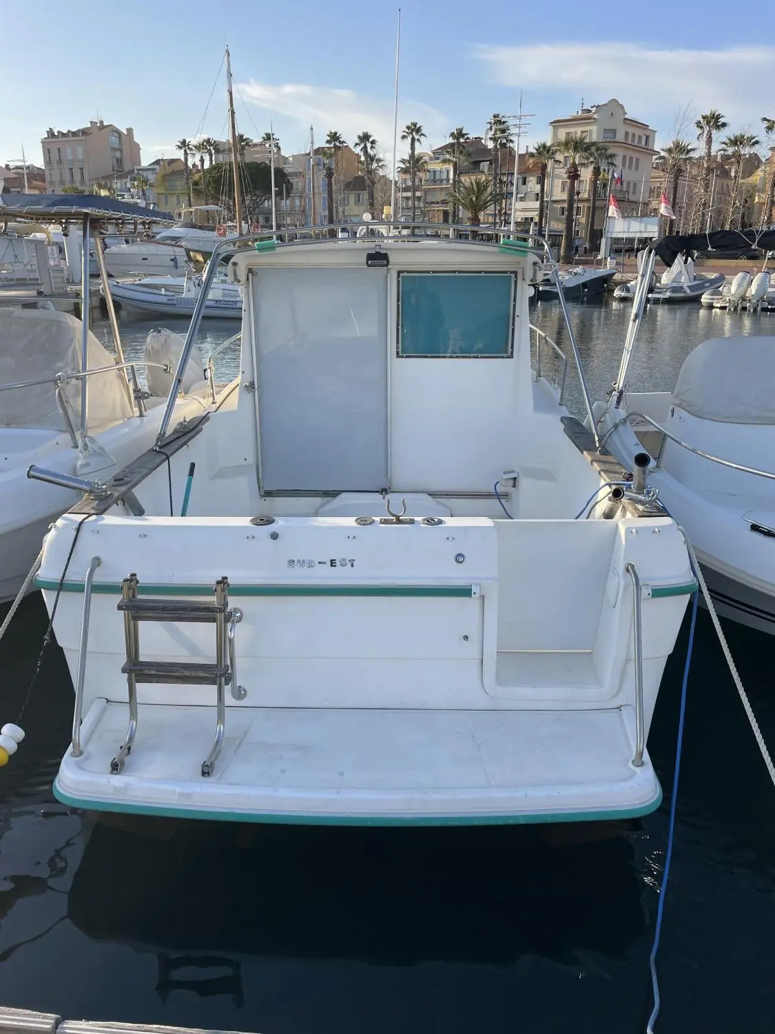 Ocqueteau Espace 625 — Vue arrière d’un bateau blanc amarré dans un port, avec plateforme et échelle de bain.