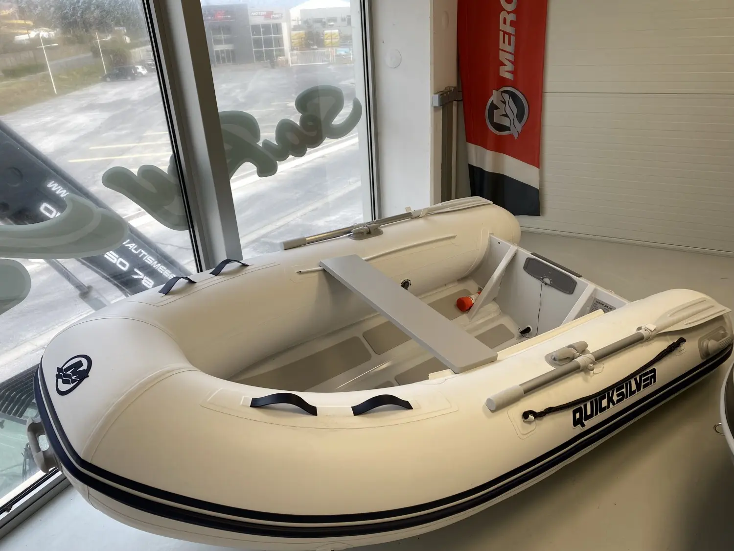 Quicksilver 270 Alu Rib — Canot pneumatique blanc exposé à l’intérieur, avec banc transversal et rames.