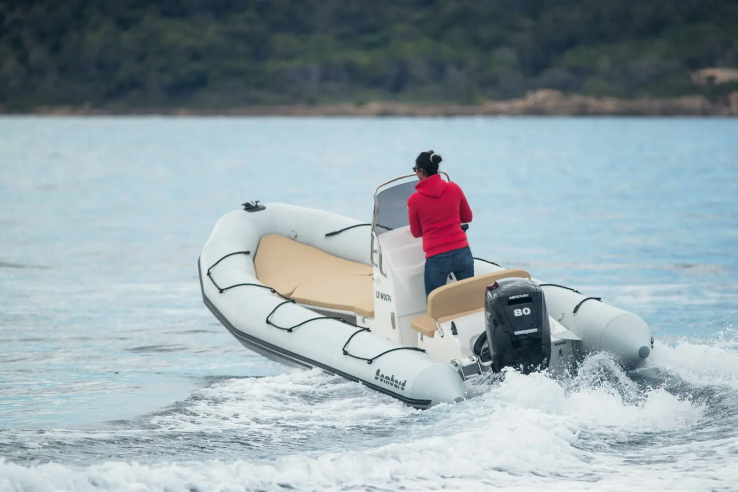 Bombard Sunrider 550 — Bateau pneumatique motorisé vu de l’arrière sur l’eau, avec une personne à bord.