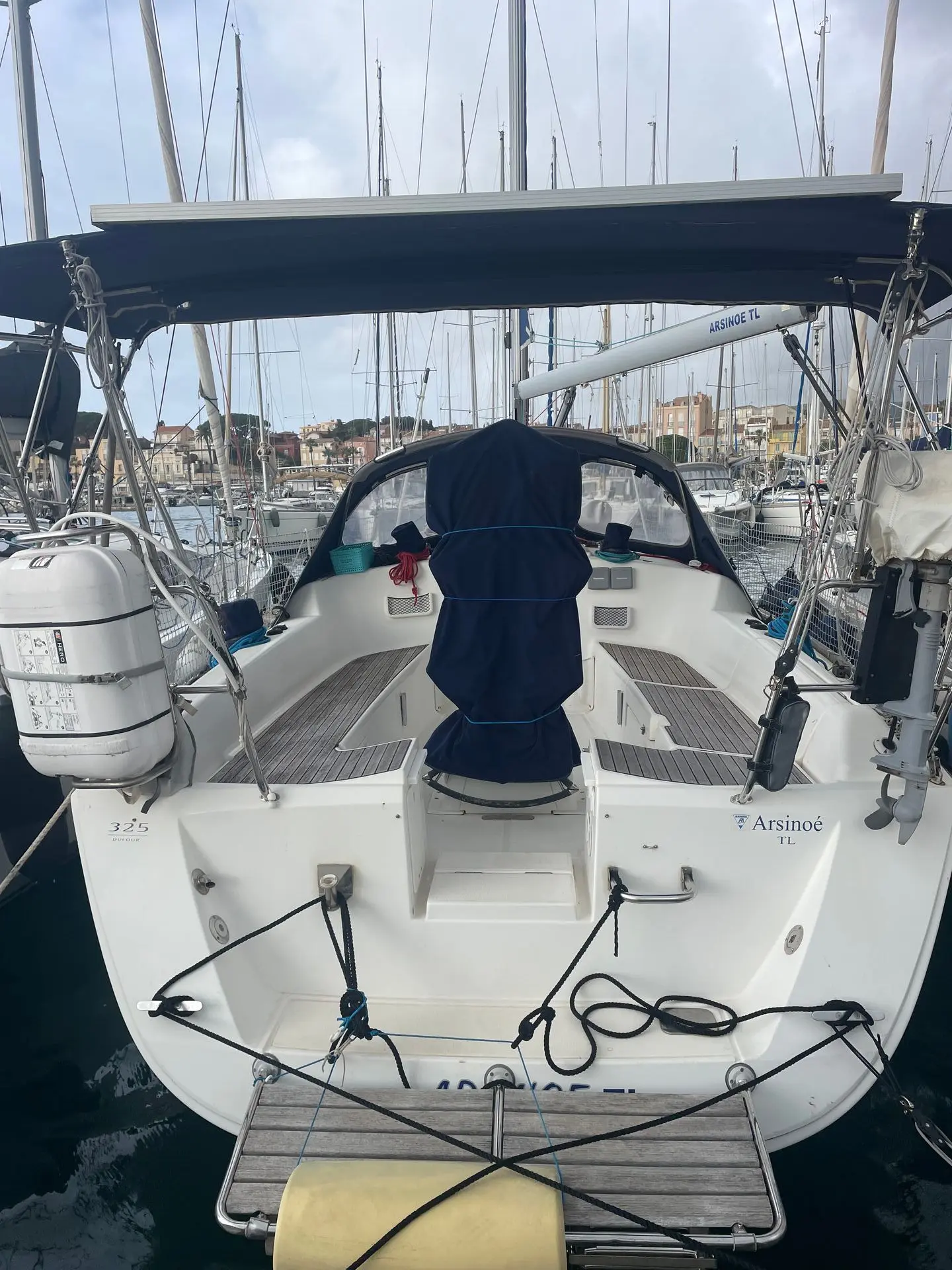Dufour 325 — Vue arrière du cockpit d’un voilier amarré au port, avec capote et gréement visibles.