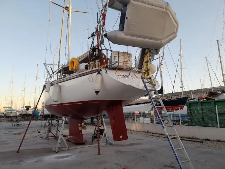 Amel Santorin Sloop — Voilier blanc photographié à terre, avec une annexe suspendue au-dessus de l’arrière.