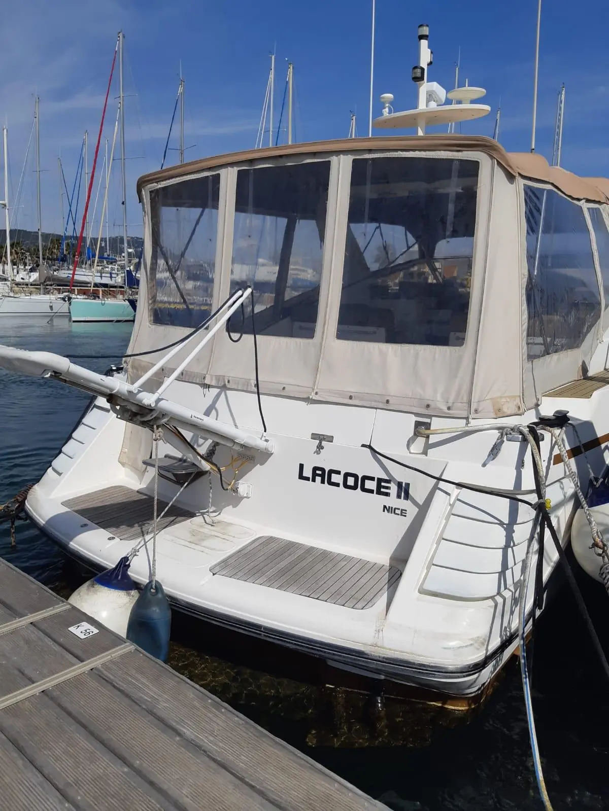 Princess 46 Riviera — Vue arrière d’un bateau à moteur amarré dans un port, avec taud de cockpit.