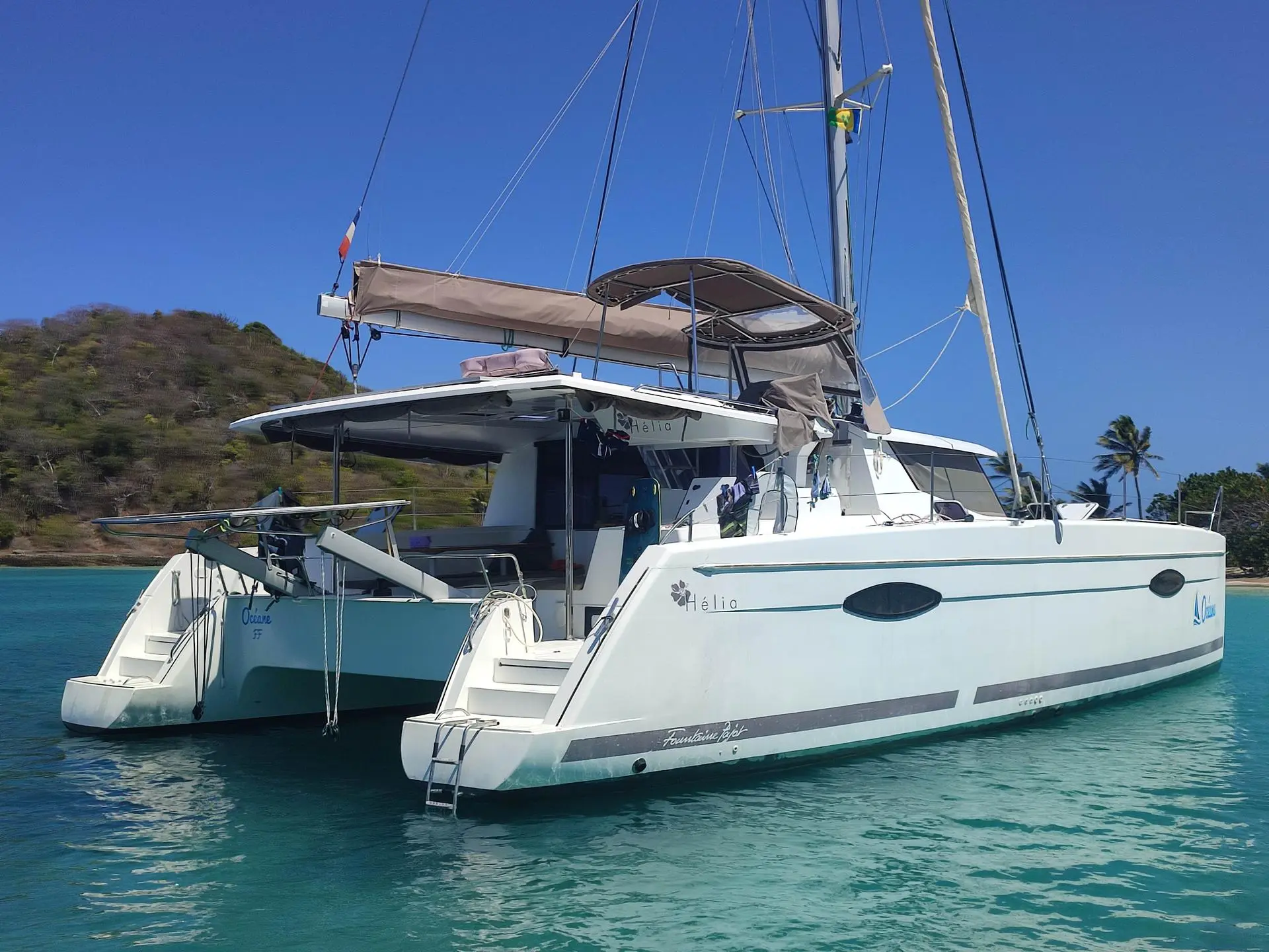 Fountaine Pajot Helia 44 — Catamaran blanc vu de trois-quarts arrière, amarré dans une baie tropicale.
