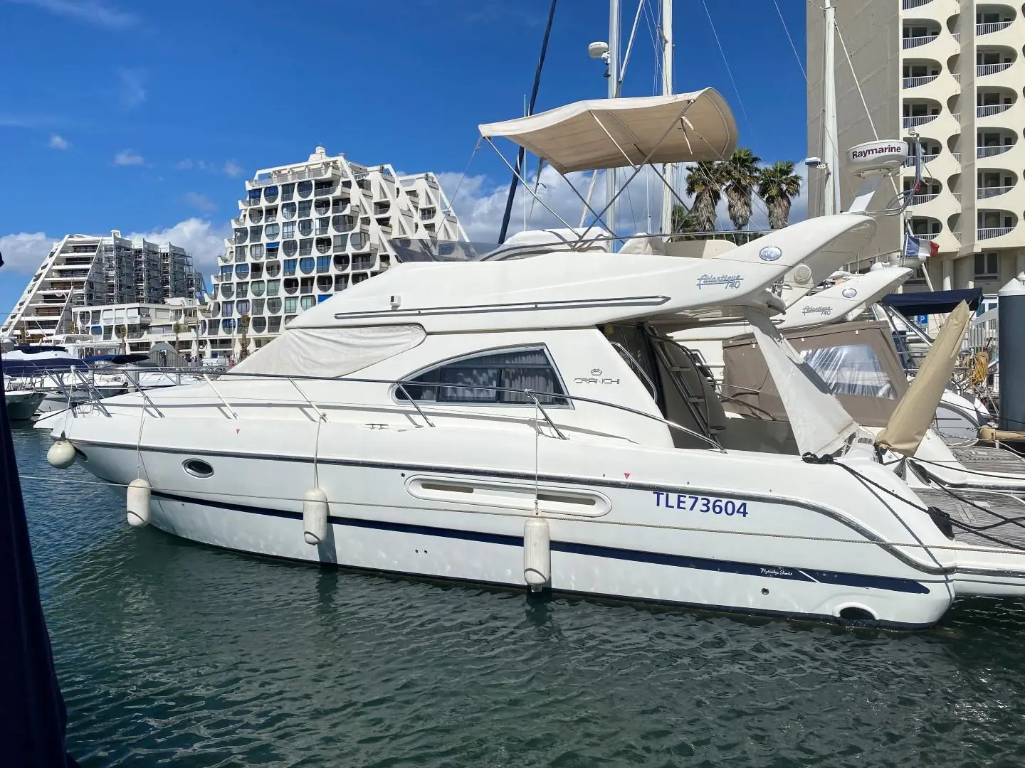 Cranchi Atlantique 40 — Bateau à moteur blanc amarré dans une marina, vu de profil latéral.