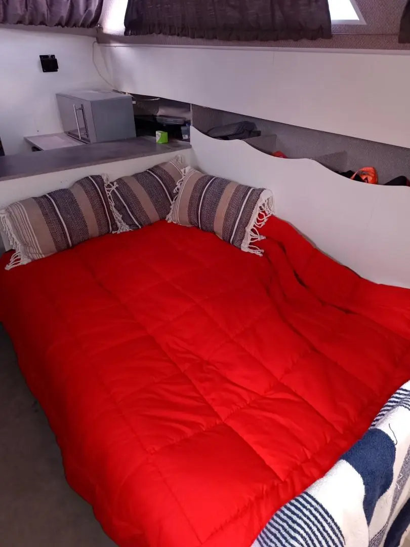 Jeanneau Imperator 900 — Couchette double avec couette rouge dans une cabine de bateau.