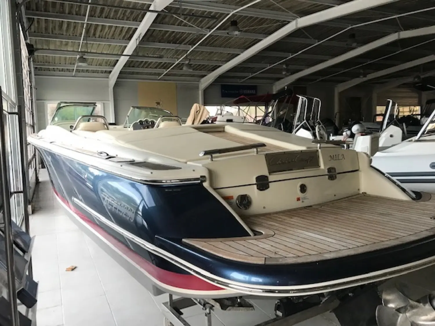 Chris Craft Corsair 27 — Bateau bleu et blanc présenté sur remorque dans un hangar, vu depuis l'arrière.
