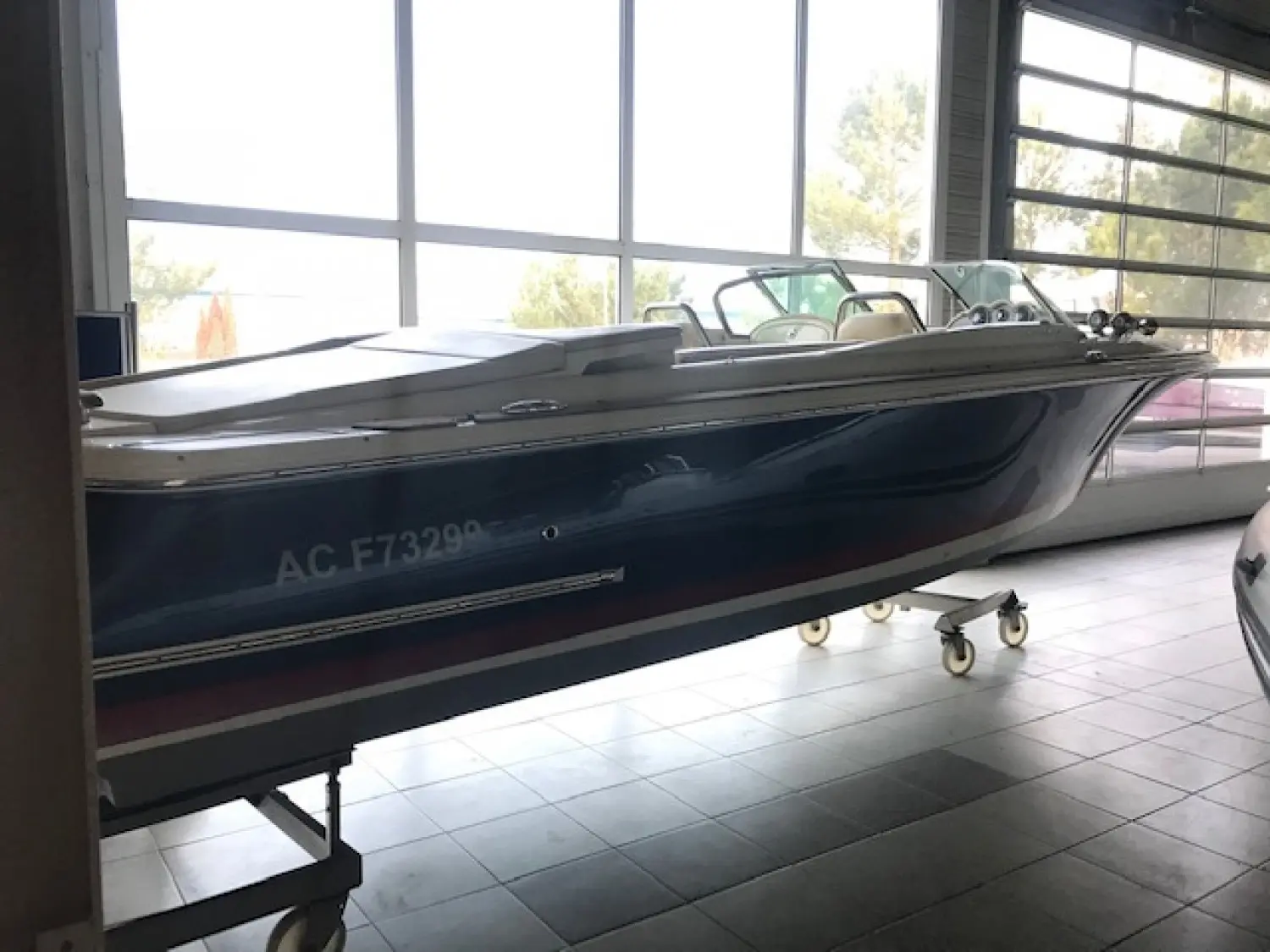 Chris Craft Corsair 27 — Bateau à moteur bleu exposé à l’intérieur d’un showroom.