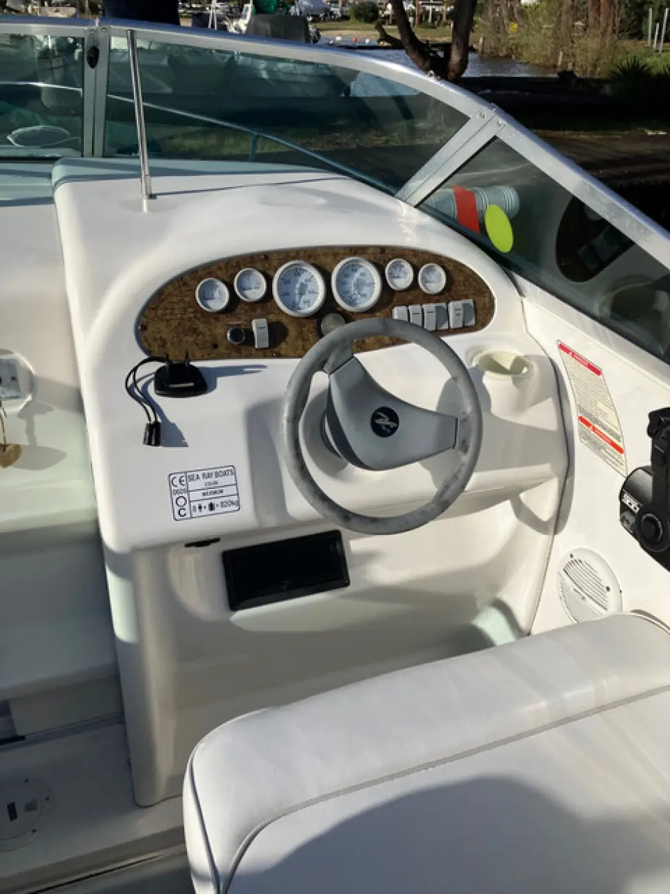 Sea Ray 215 Express — Poste de pilotage avec instruments, volant et pare-brise.