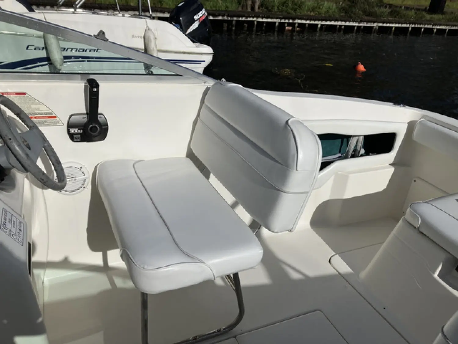 Sea Ray 215 Express — Vue du poste de pilotage et des sièges d’un bateau, avec un autre bateau en arrière-plan.