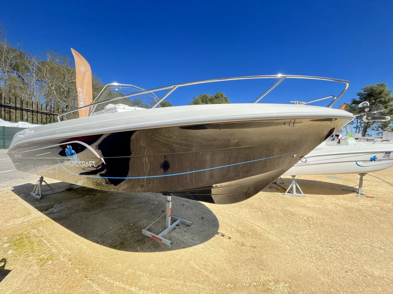 Pacific Craft 670 — Bateau à moteur blanc exposé sur bers, vu de trois quarts dans un chantier naval.