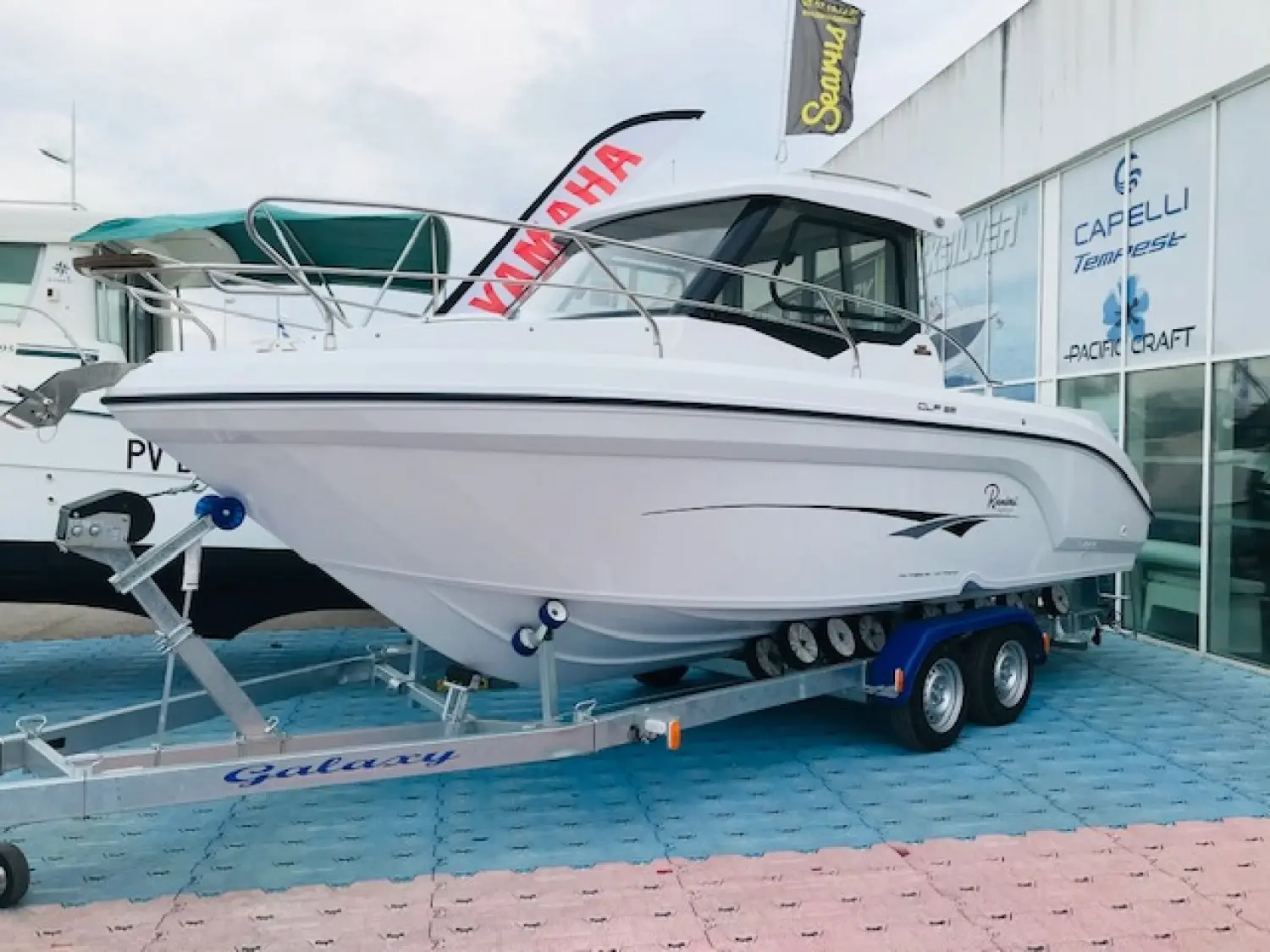 Ranieri Clf 22 — Bateau blanc à cabine exposé sur une remorque double essieu devant un hall.