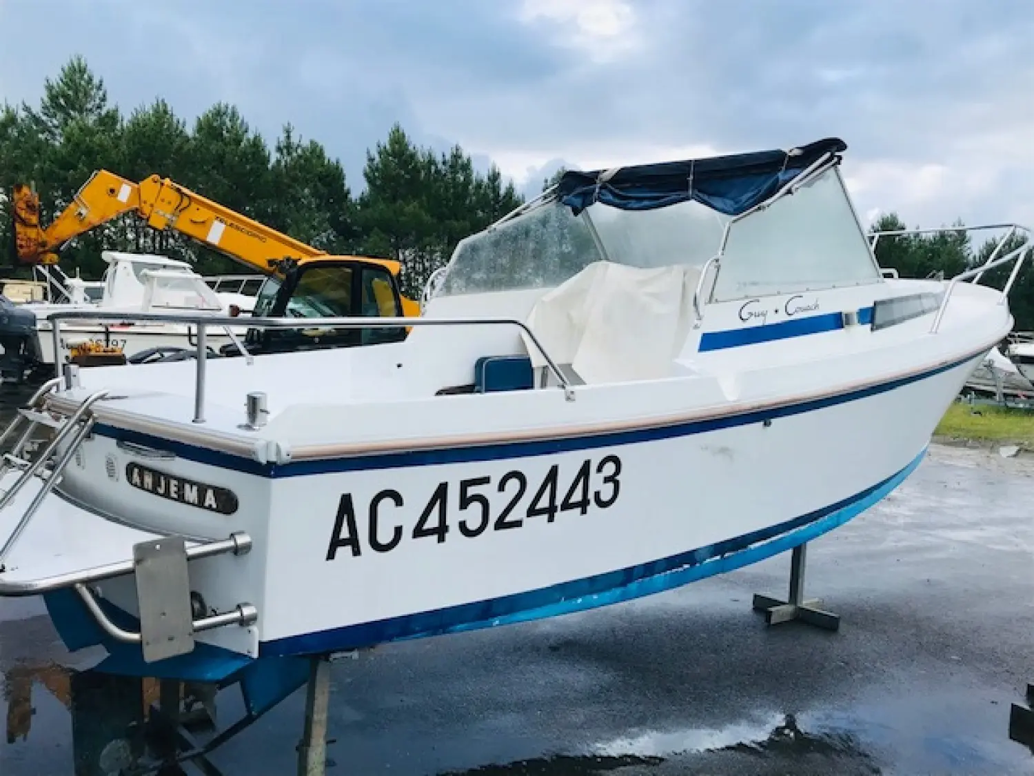 Guy Couach 580 — Bateau à moteur blanc et bleu photographié à terre, sous une bâche de cockpit.