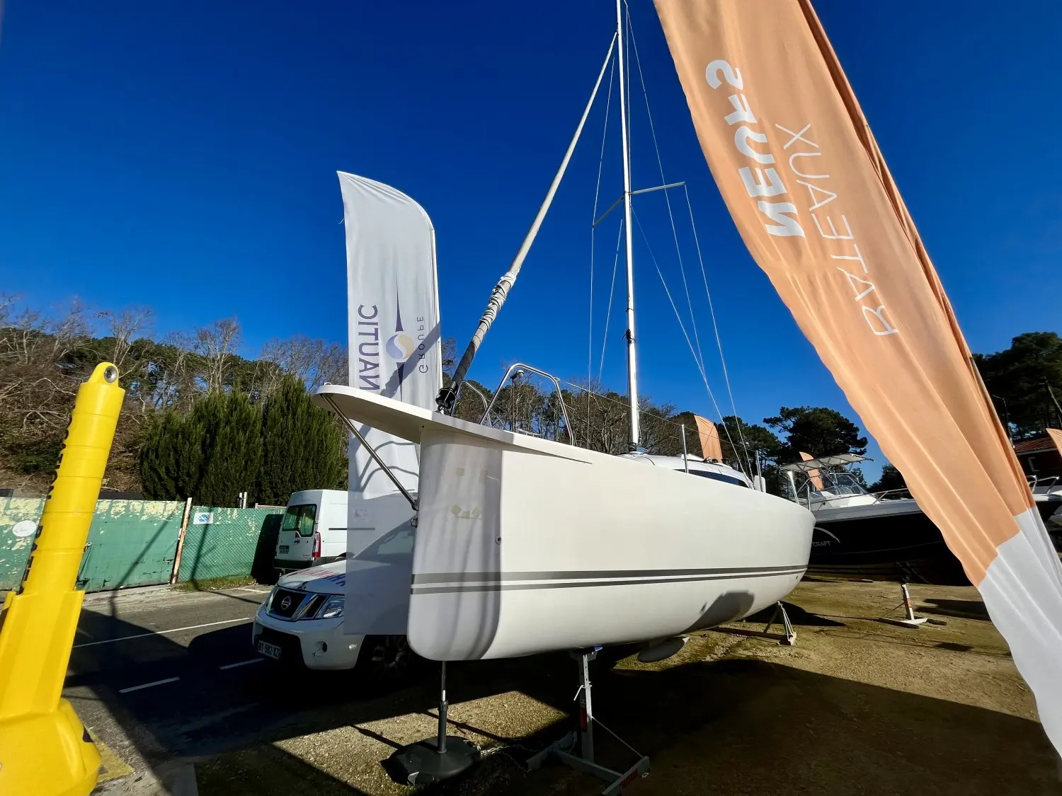 Viko Boats Viko 22 S — Voilier blanc présenté à terre sur un support, entre des fanions publicitaires.