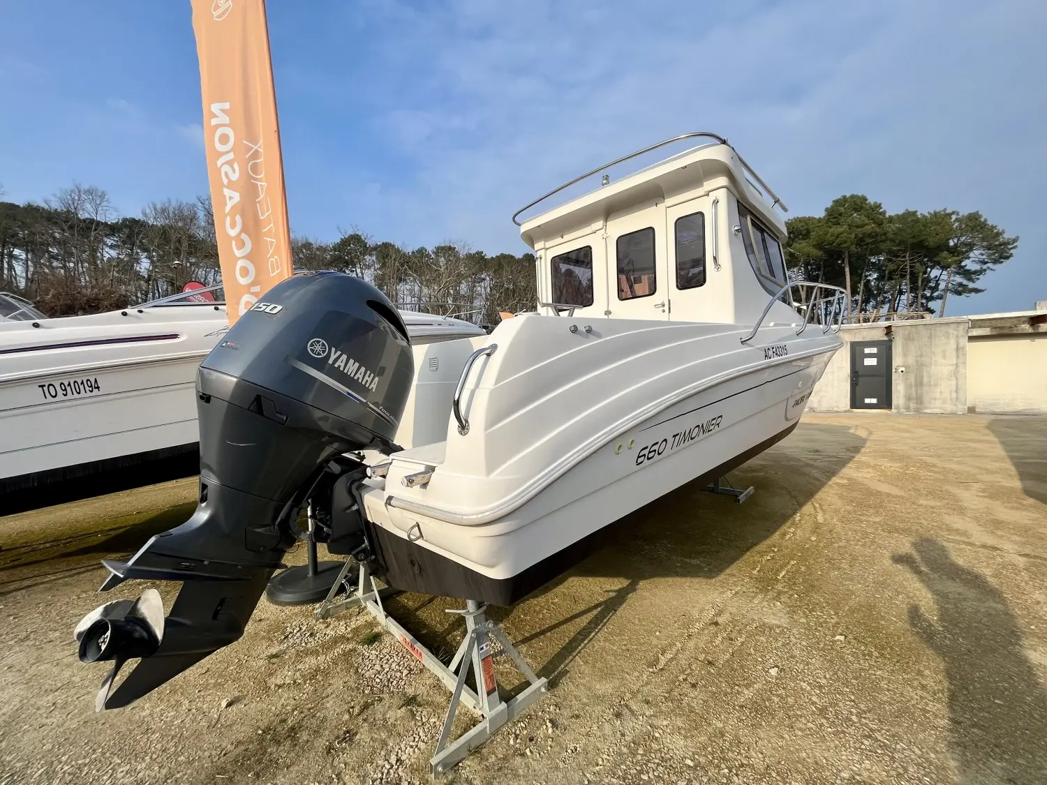 Pacific Craft 660 Timonier — Bateau à cabine présenté sur remorque, vu de trois quarts arrière avec moteur hors-bord.