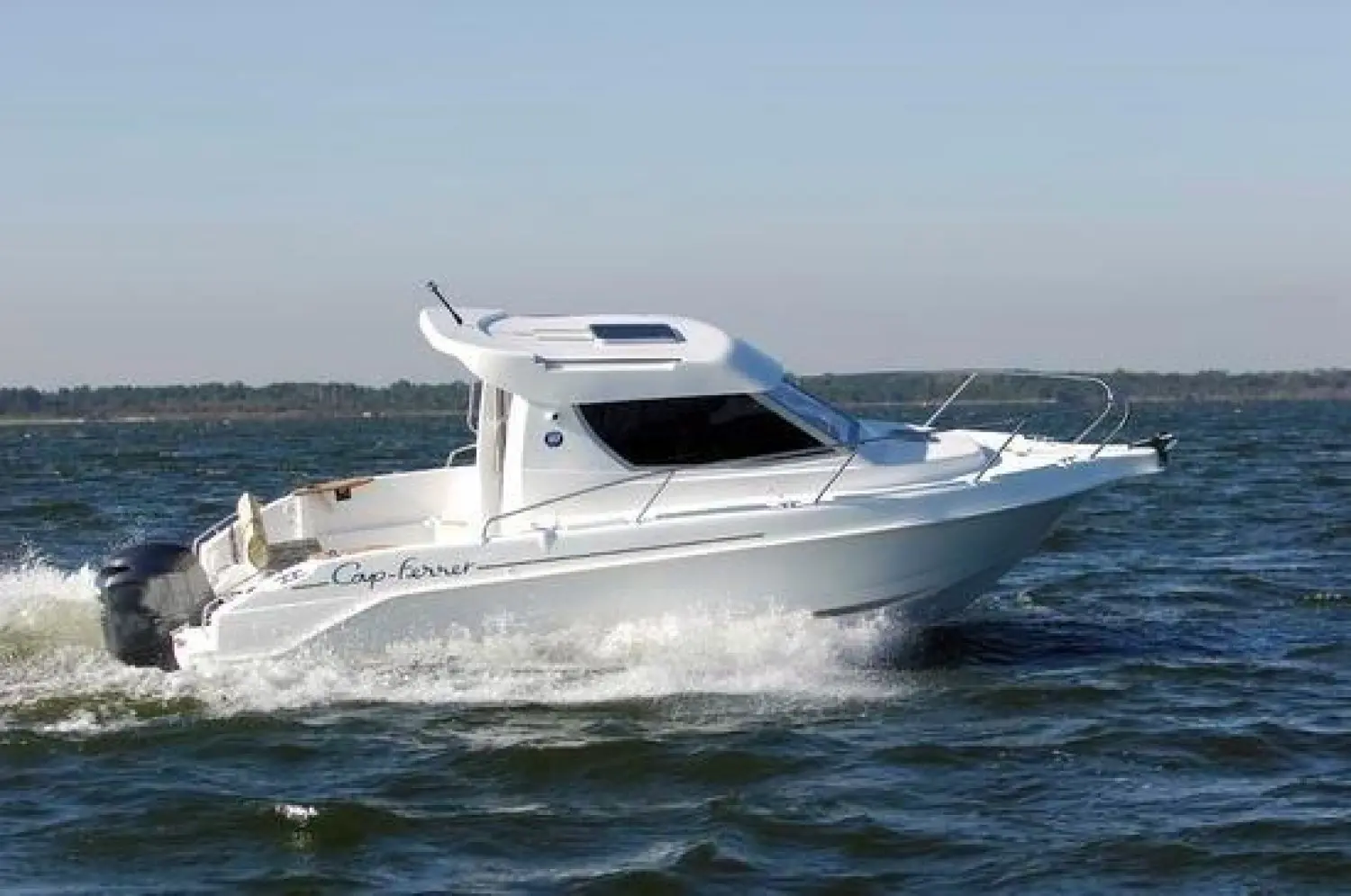 B2 Marine Cap Ferret 228 — Bateau blanc à cabine naviguant sur une mer agitée, vu de trois-quarts.
