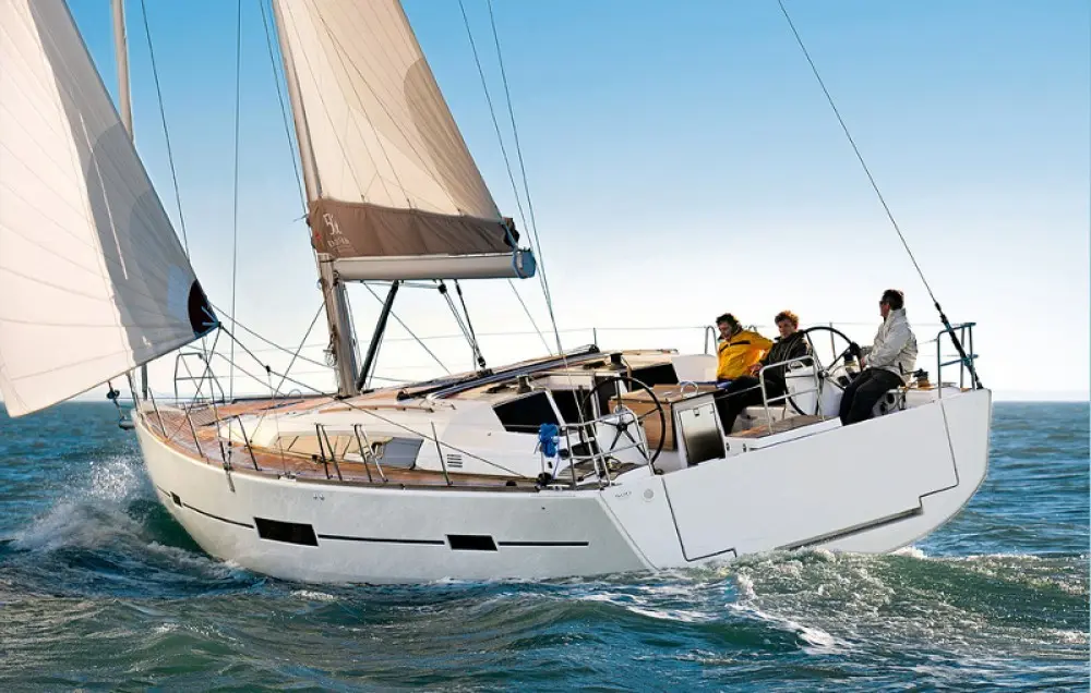 Dufour 500 Grand Large — Voilier blanc naviguant à la voile sur mer agitée, vu de trois quarts arrière.