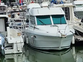 Jeanneau Merry Fisher 805 — Bateau à moteur blanc vu de trois quarts avant dans une marina.