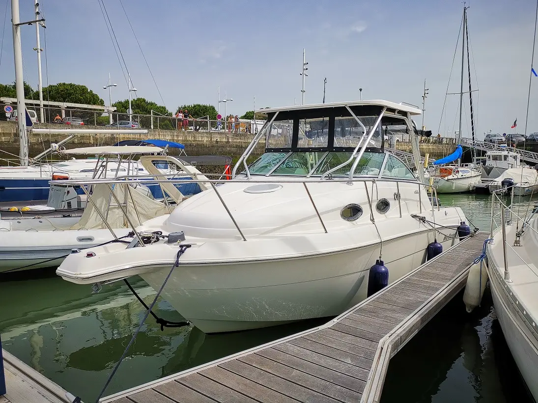 Wellcraft Coastal 270 — Bateau à moteur blanc amarré dans un port, vu de trois quarts avant.