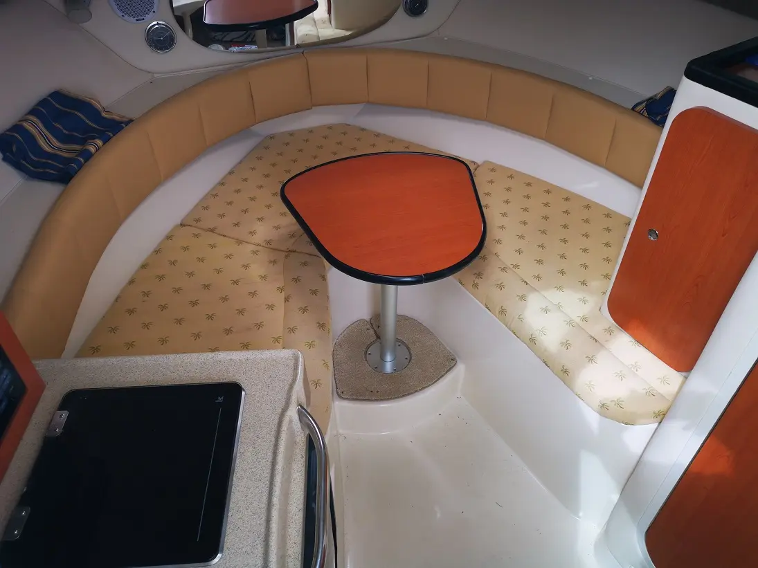 Wellcraft Coastal 270 — Vue de la dinette avant avec banquettes, table centrale et rangements.