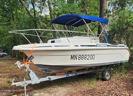 Guymarine GM 540 — Bateau à moteur blanc sur remorque, équipé d’un taud bleu, dans un sous-bois.