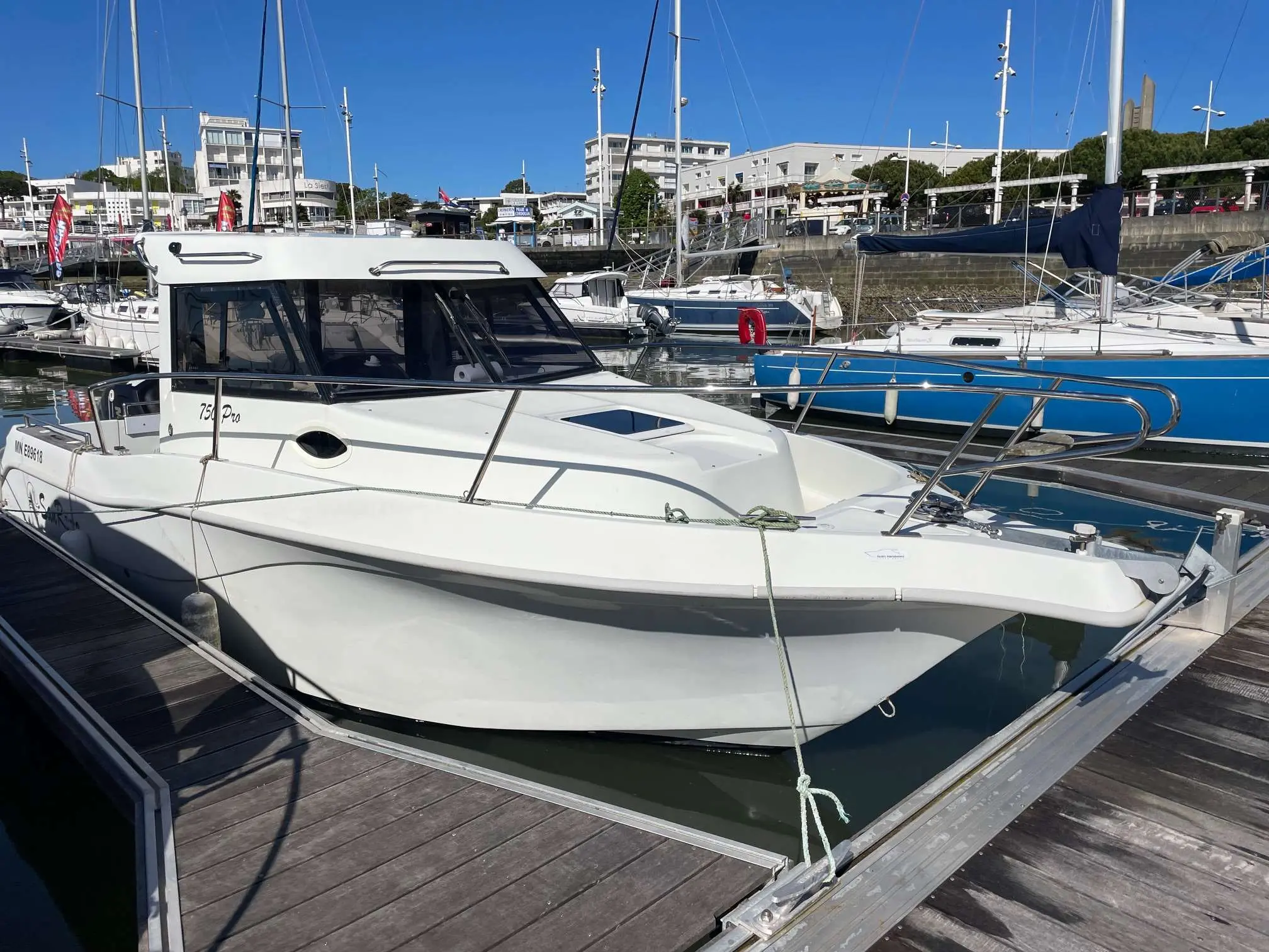 San Remo 750 Fisher — Bateau à moteur blanc amarré dans une marina, vu de trois quarts bâbord.