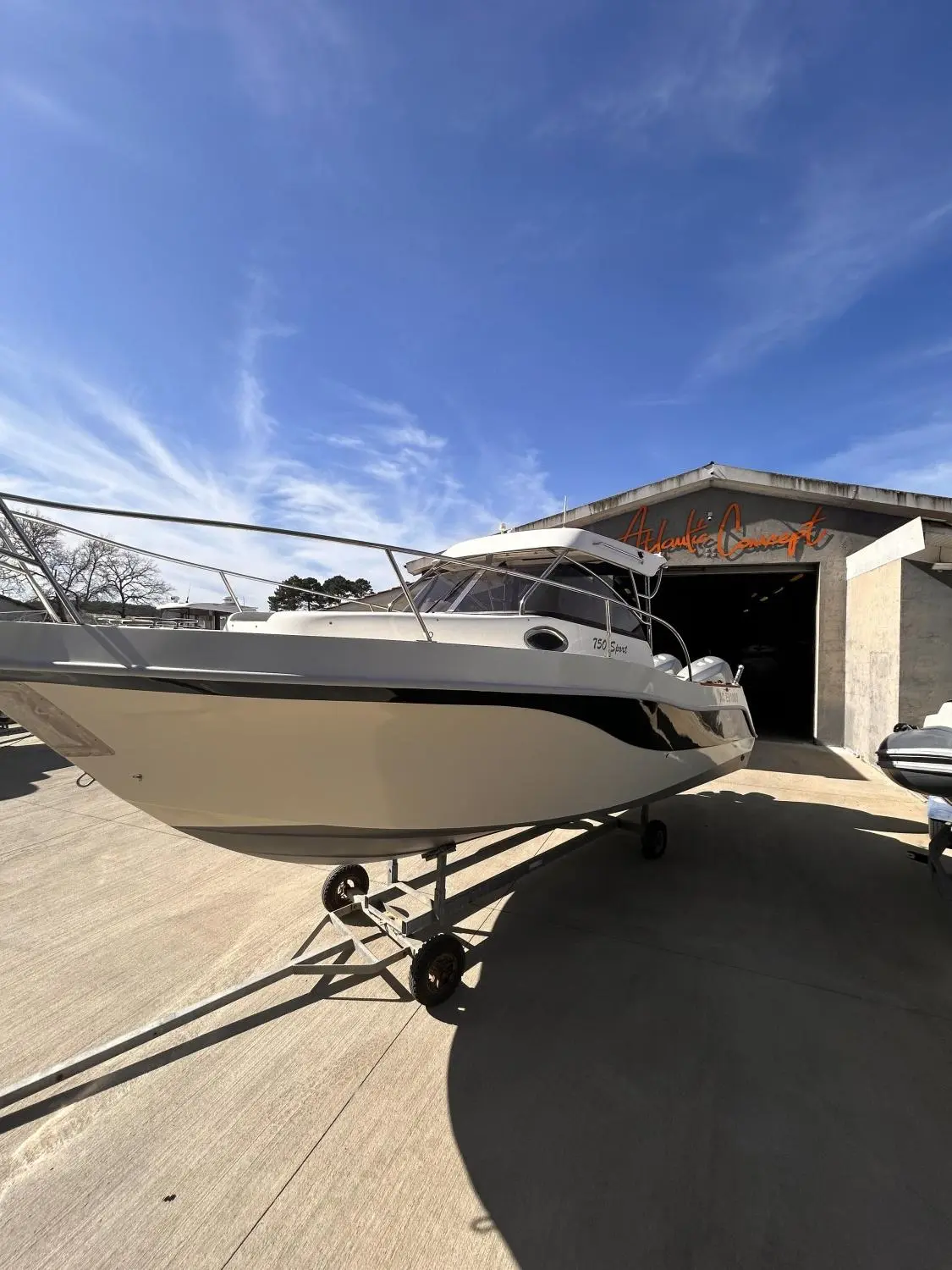 San Remo 750 Sport — Bateau à moteur blanc sur remorque, photographié de trois quarts devant un hangar.