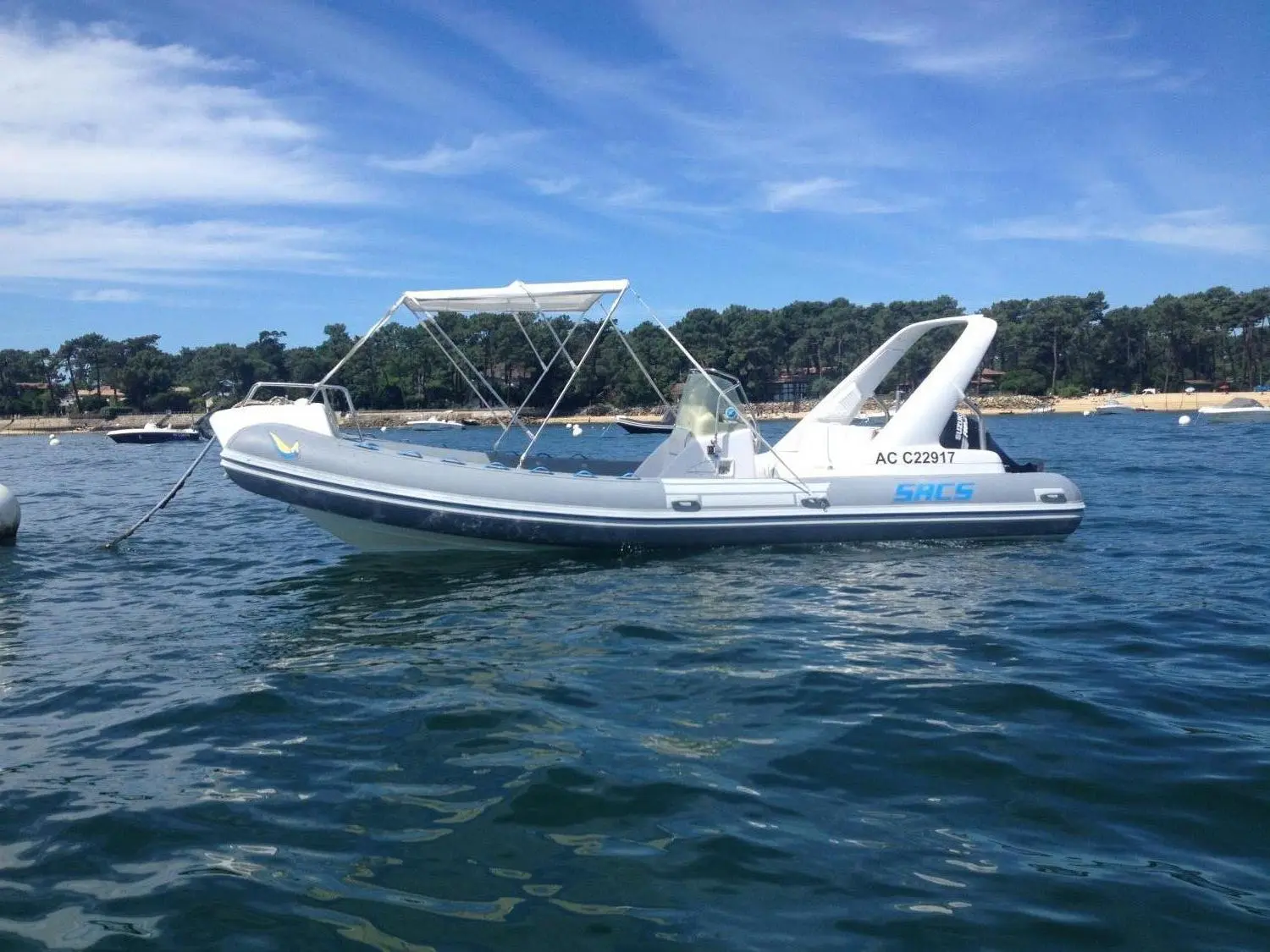 Sacs S 680 — Semi-rigide blanc SACS amarré sur l’eau, avec console centrale et taud pliant.