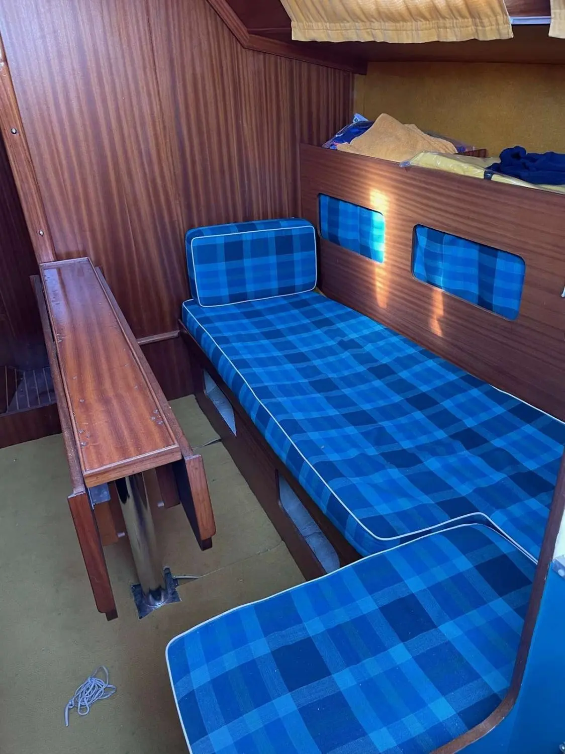 Gibert Marine Gib Sea 30 — Cabine intérieure avec couchettes bleues, banquette et table en bois.