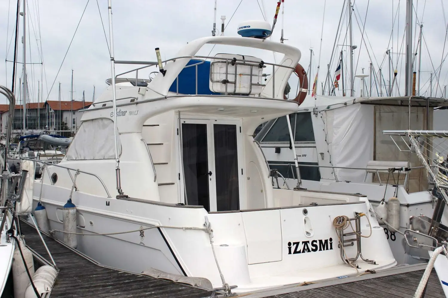 Astinor 1000 LX — Bateau à moteur blanc vu de trois quarts arrière dans une marina.