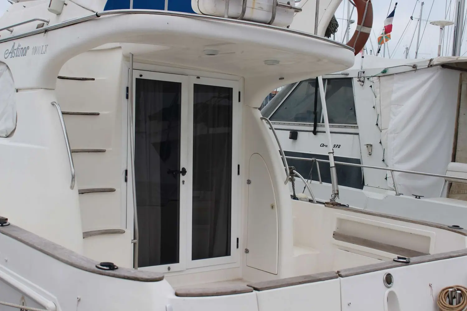 Astinor 1000 LX — Vue rapprochée de l’arrière et du cockpit d’un bateau blanc en marina.