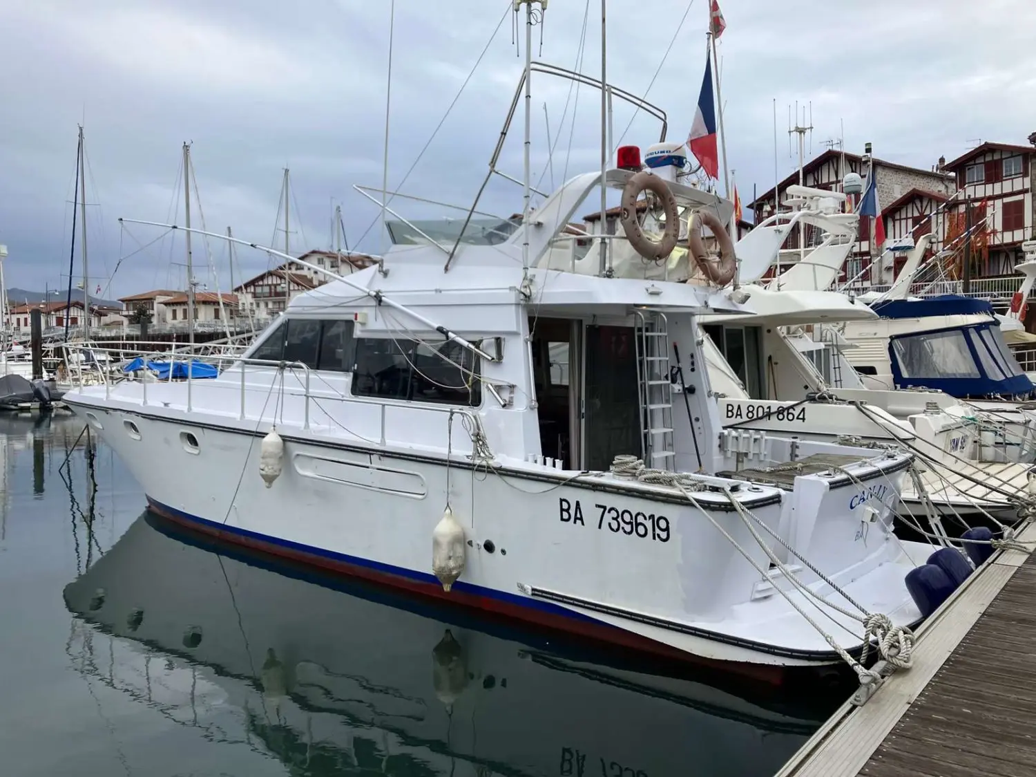 ACM 1300 — Bateau à moteur blanc amarré dans un port, vu de trois quarts arrière.